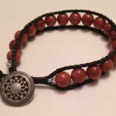 Brown glitter glass bead woven with black cord and silver button