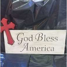 Custom made plaque with a cross and the words " God Bless America" carved into the  wood.